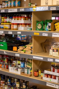 Shelf stable food products stacked on shelves in a food bank. Photo by Aaron Doucett via Unsplash.
