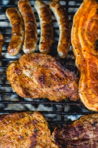 Chicken, bacon, and sausages cooked on a barbeque. Photo by Marcus Spiske via Unsplash.