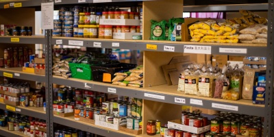 Shelf stable food products stacked on shelves in a food bank. Photo by Aaron Doucett via Unsplash.
