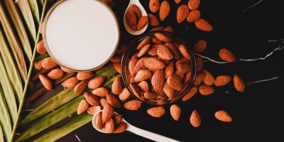 A cup of almonds and a cup of almonds milk. Photo by dhanya purohit via Unsplash.
