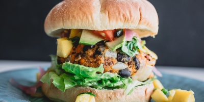 Image: image of a plant-based burger in front of a dark background. Photo by Deryn Macey via Unsplash