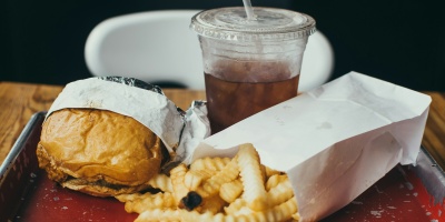 A tray of fast food including a burger, fries, and a drink. Photo by Christopher Williams on Unsplash.