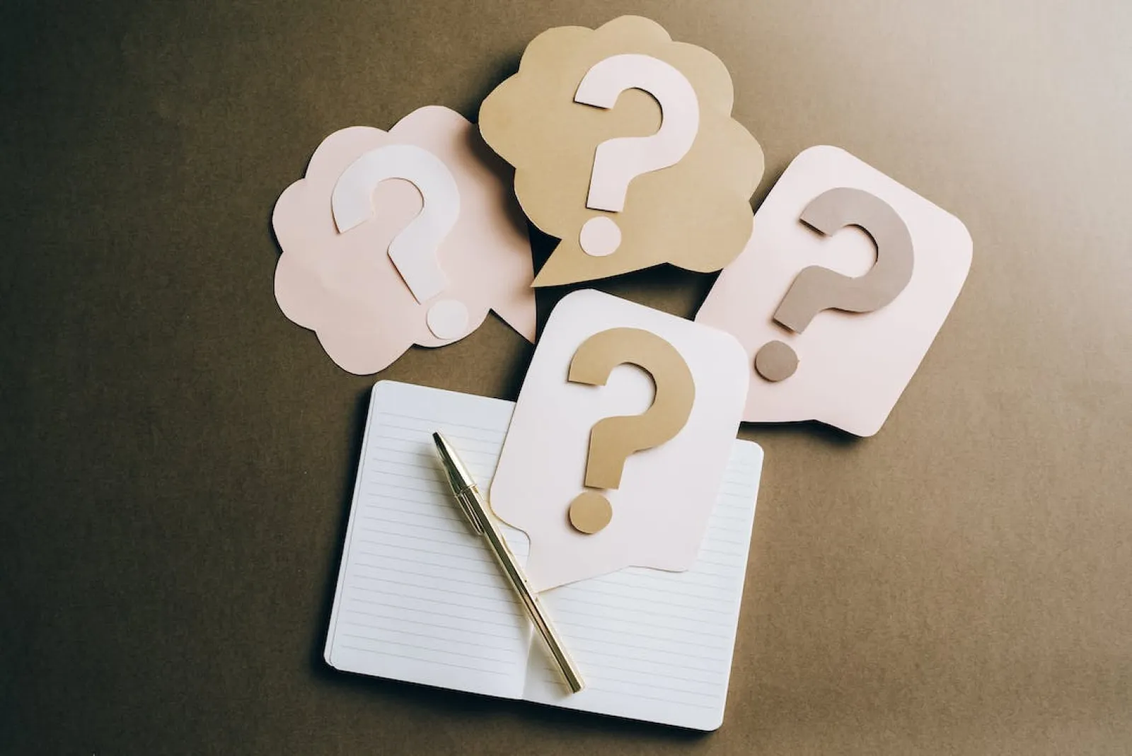 FAQs cover image featuring 4 speech bubbles with question marks next to notepad and pen