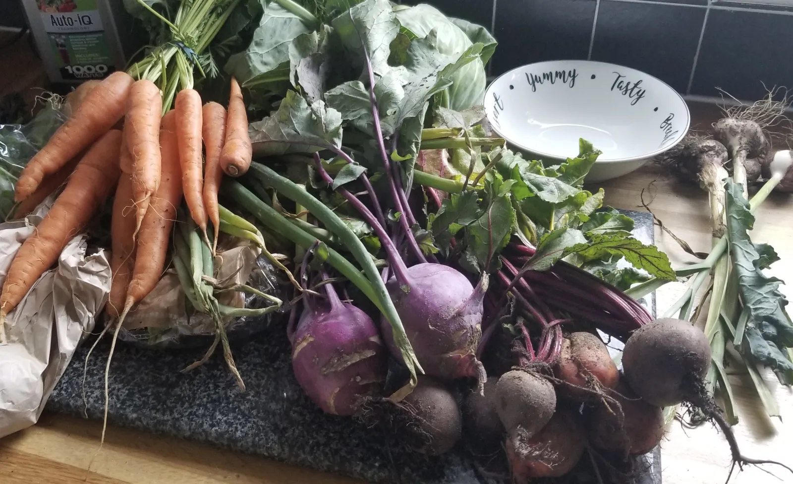 Photograph (taken by Rach Headings, in her kitchen) of veg box food including carrots, beets and green onions