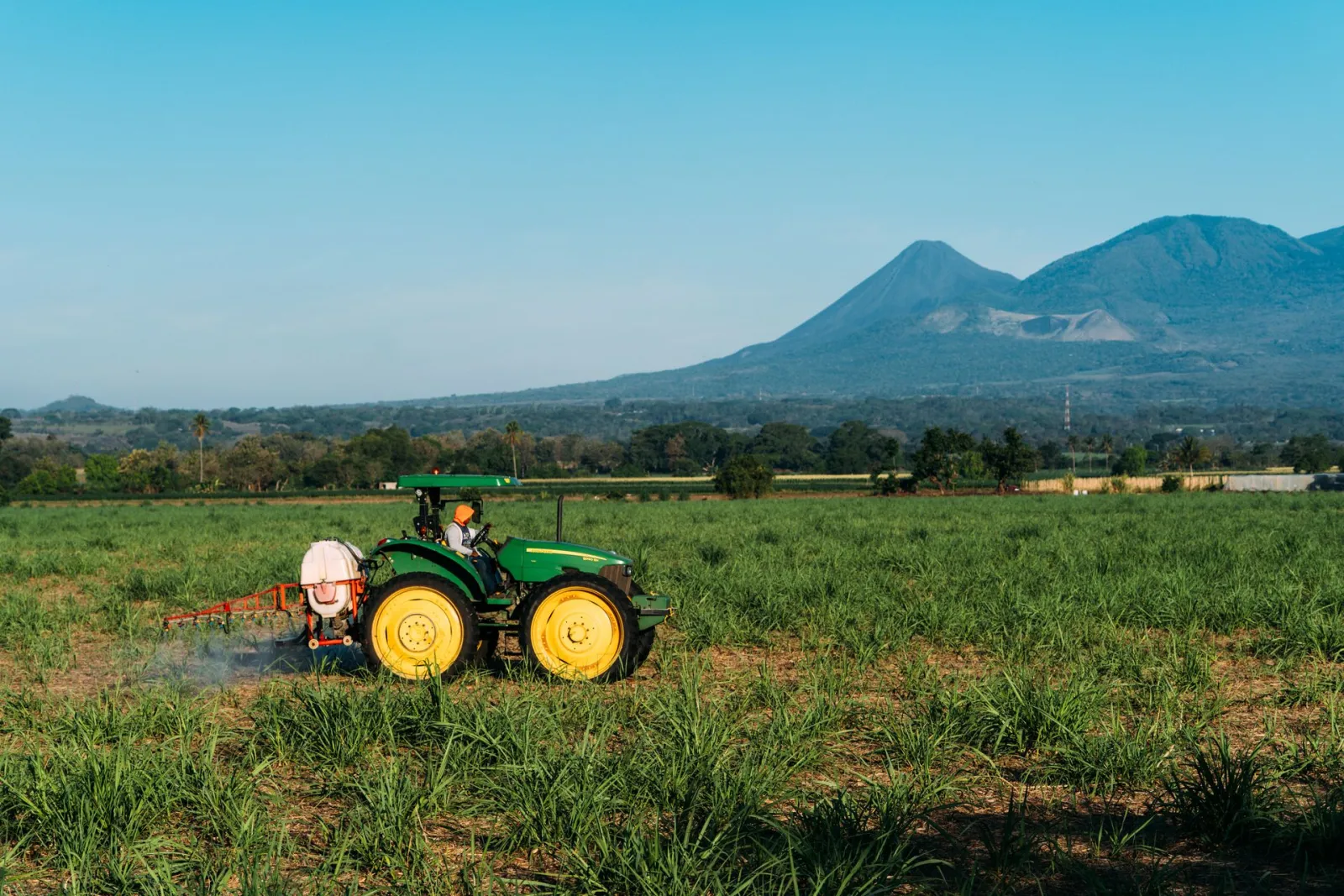 Photo of tractor in field with mountains behind. Credit: Edu Raw via Pexels