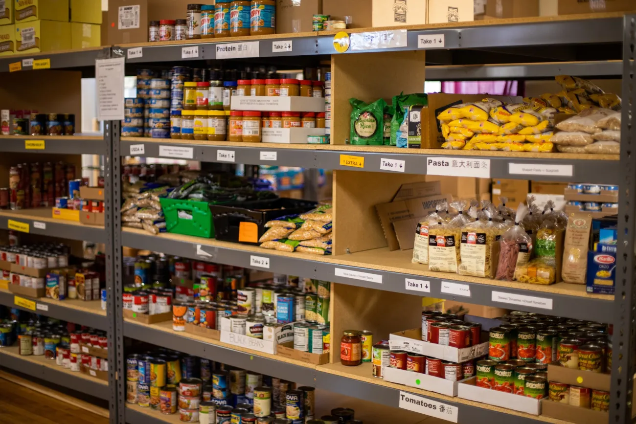 Shelf stable food products stacked on shelves in a food bank. Photo by Aaron Doucett via Unsplash.