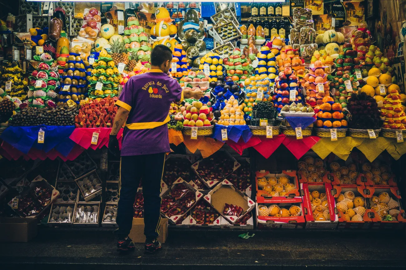 Photo of food market trader in São Paulo. Photo by D A V I D S O N L U N A via Unsplash