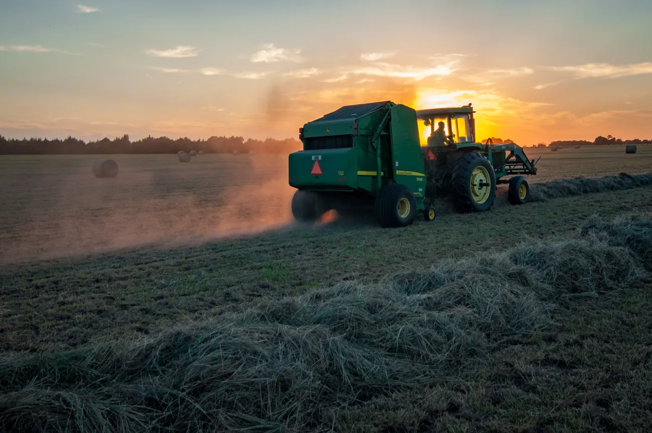A tractor emitting fumes whilst ploughing a field. Photo by Jed Owen via Unsplash