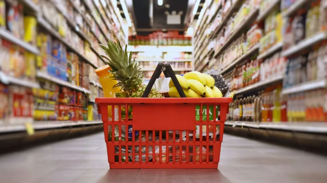 A shopping basket full of fruit in the middle of a grocery store. Image via Cornell University
