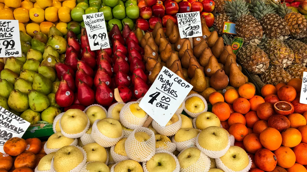 A market stall with apples, pears, oranges and pineapples. Photo by Rajiv Perera via Unsplash