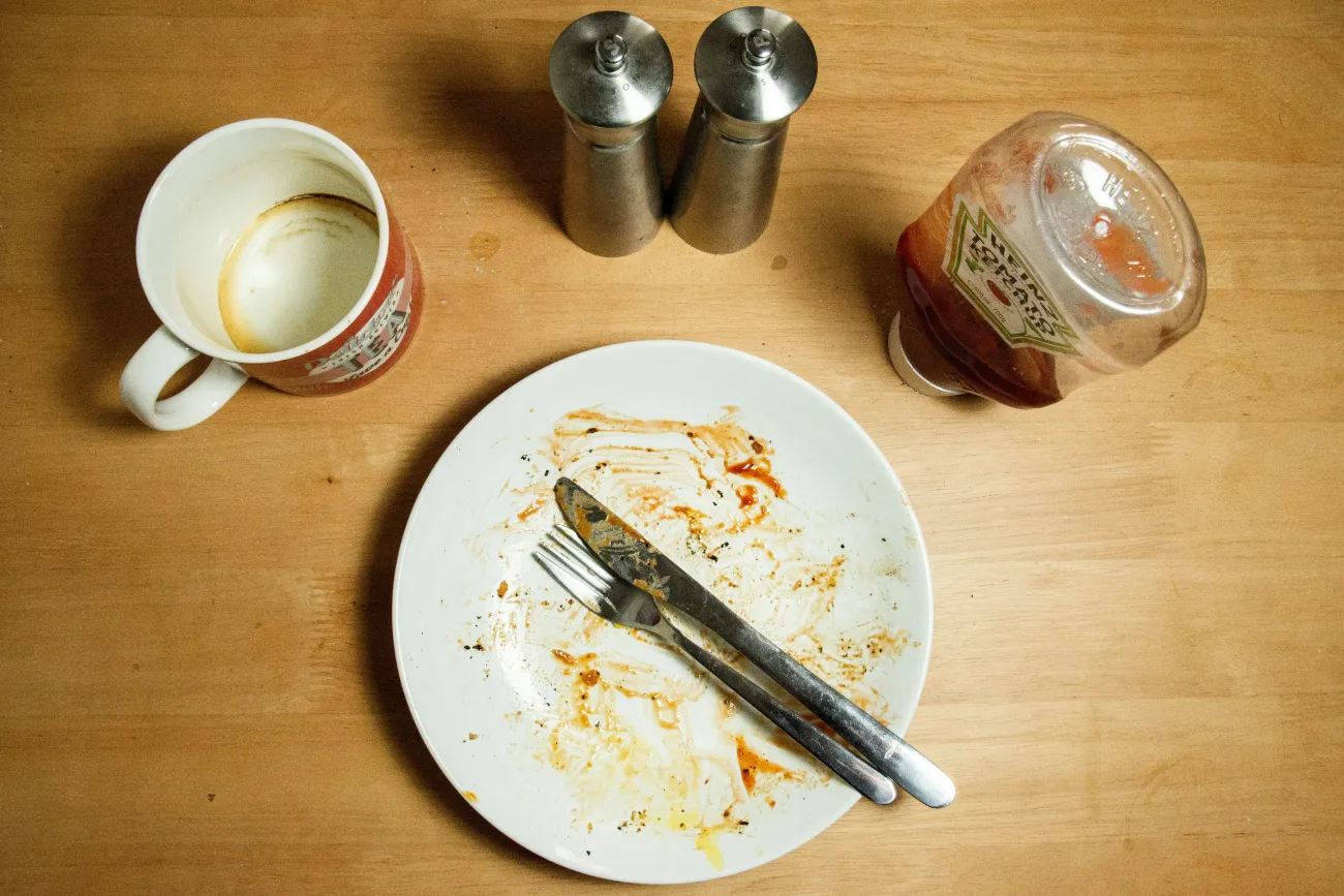 Photo of a finished plate of food and an empty mug. Photo by Richard Bell via Unsplash 