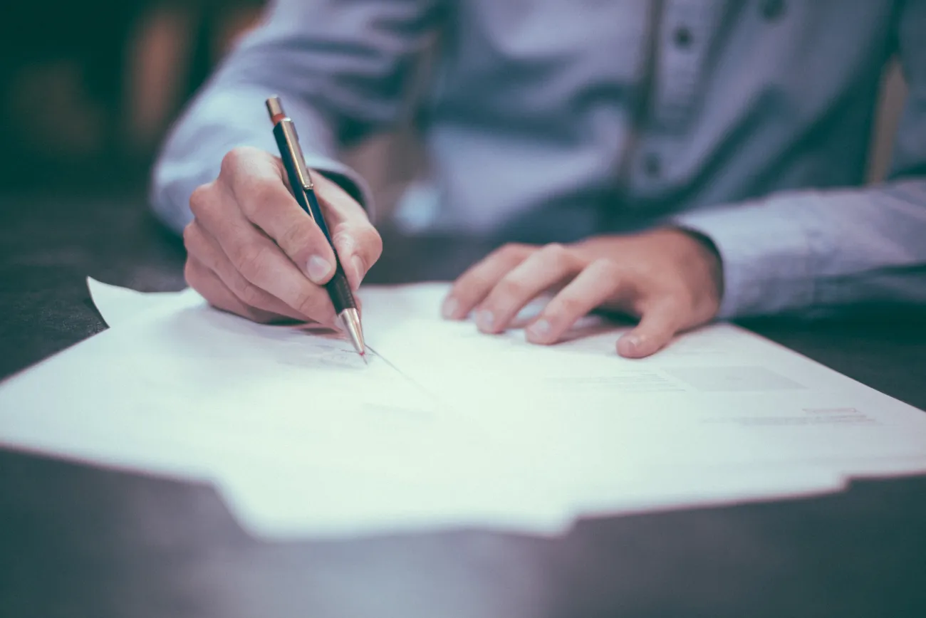 Photo of a man penning a letter. Photo by Scott Graham via Unsplash