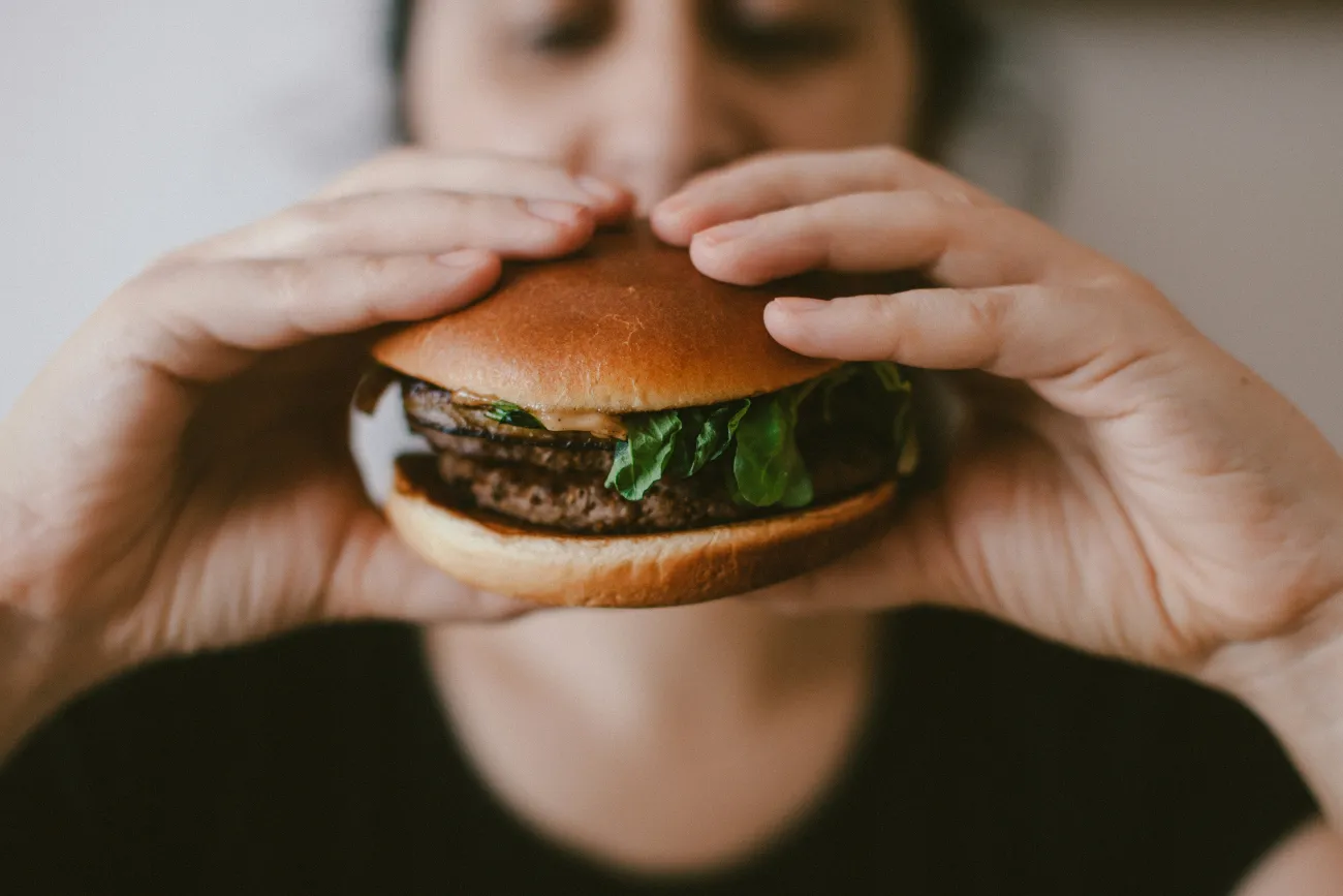Image of a person eating a hamburger. Image by Szabo Viktor via Unsplash