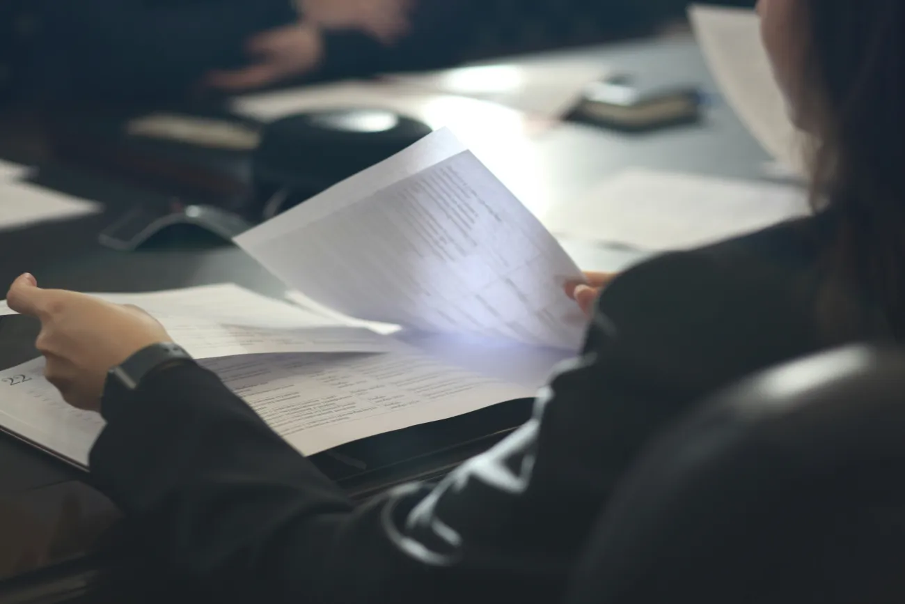 A woman shuffles through documents. Photo by Anastassia Anufrieva via Unsplash.