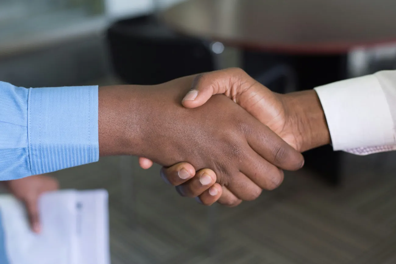 Two people shake hands. Photo by Cytonn Photography via Unsplash.
