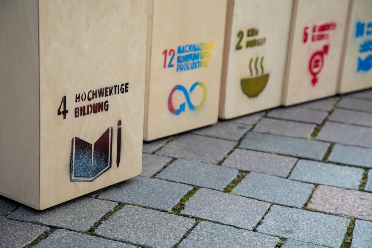 Wooden boxes labeled with sustainable development goals. Photo by Katja Anokhina via Unsplash.