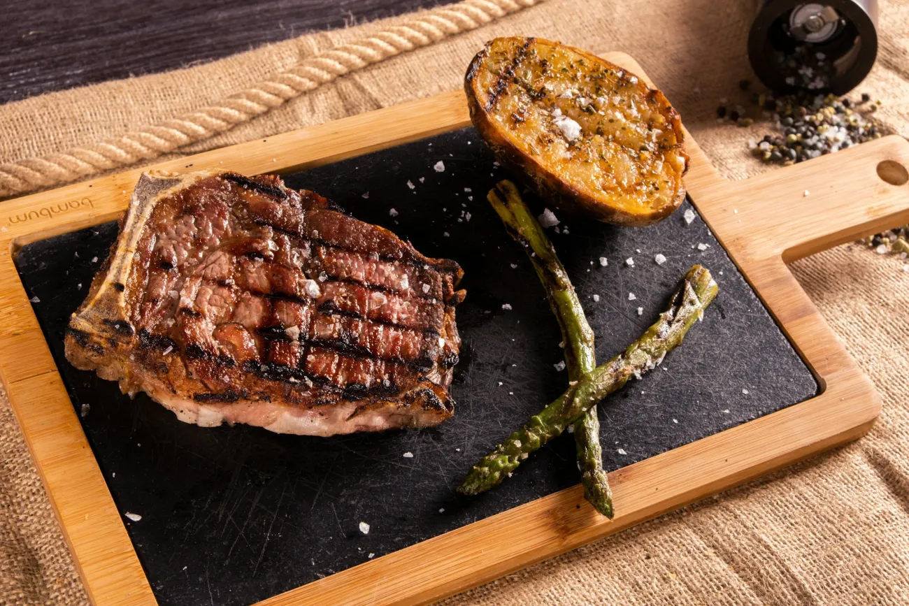 A grilled steak and a potato served on a slate. Photo by Ömer Haktan Bulut via Unsplash.