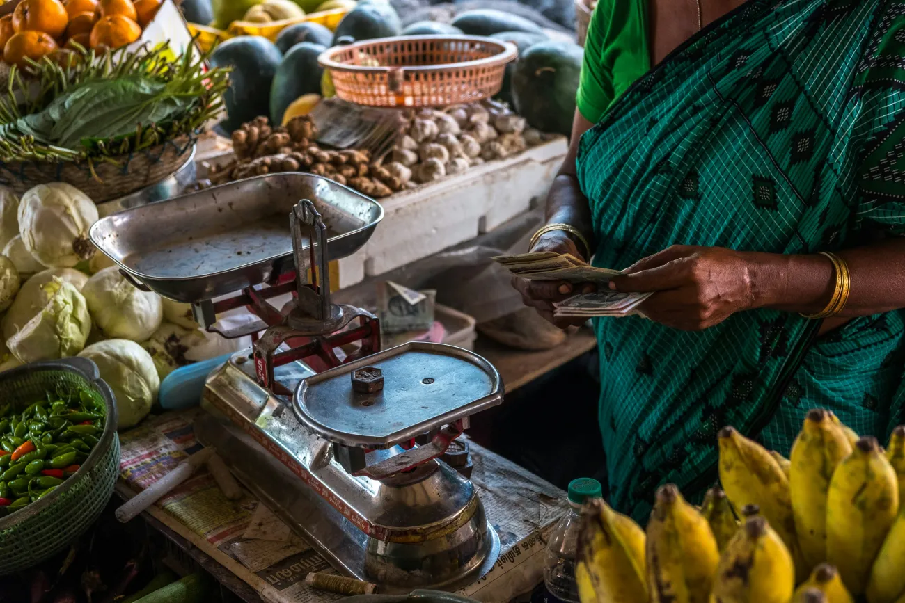 A woman with a scale selling fruit. Photo by Pau Casals via Unsplash.