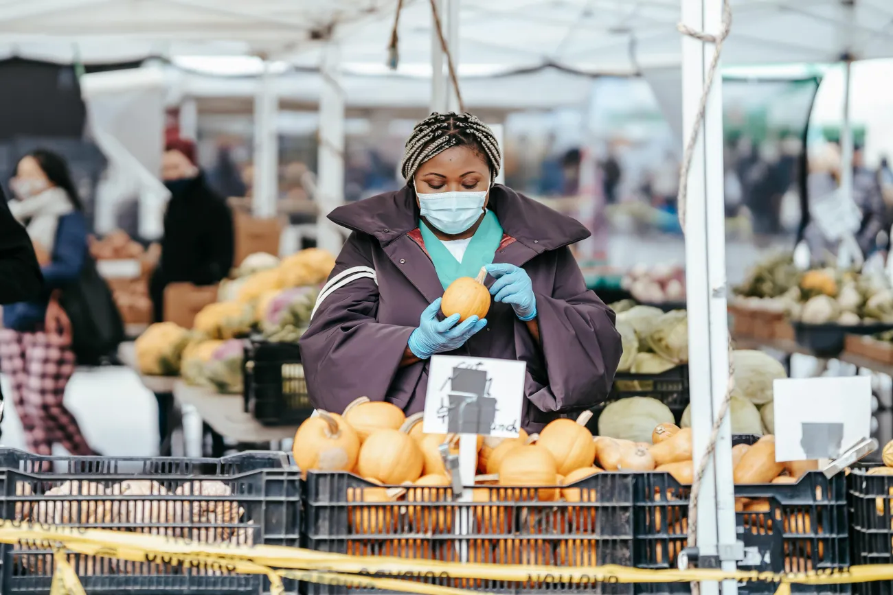 Photo of woman buying fruit with mask. Credit Laura James via Pexels. 