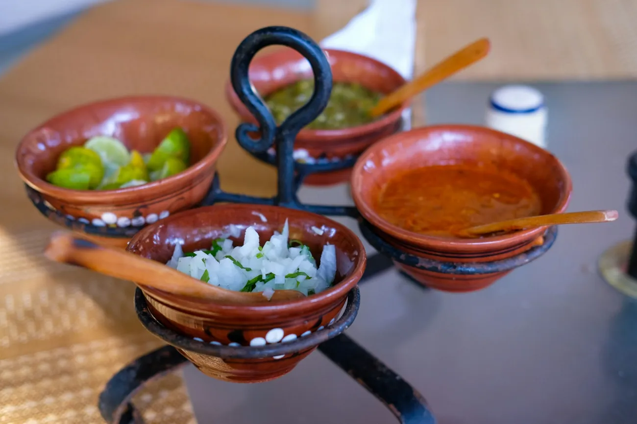 Sauces and toppings in small clay bowls at a restaurant in México. Photo by Edgar Cavazos via Unsplash.