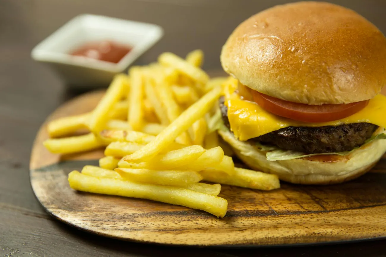 Burger and chips on wooden plate. Credit: Foodie Factor via Pexels