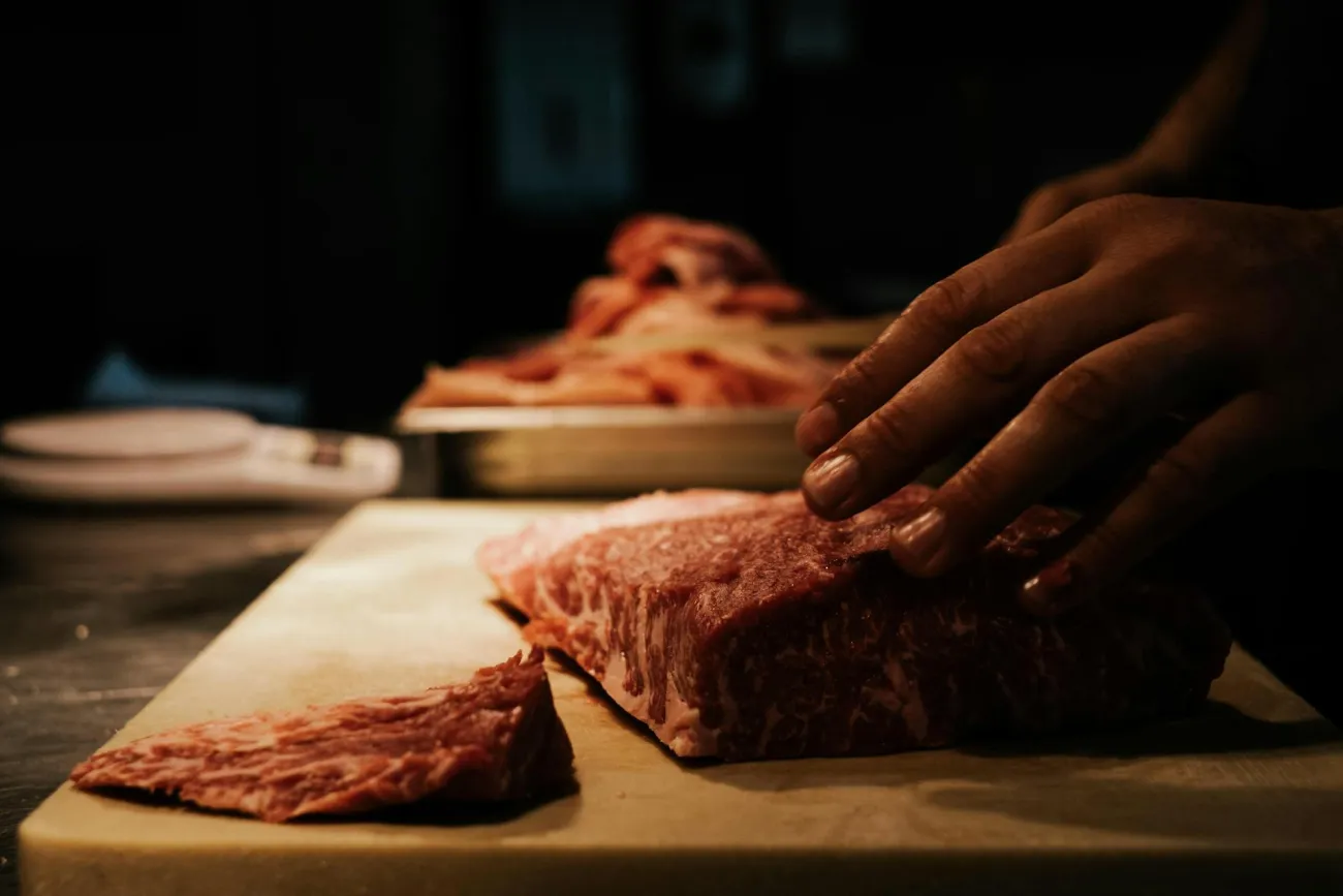 Hands pushing read meat into chopping board. Credit: Rachel Claire via Pexels