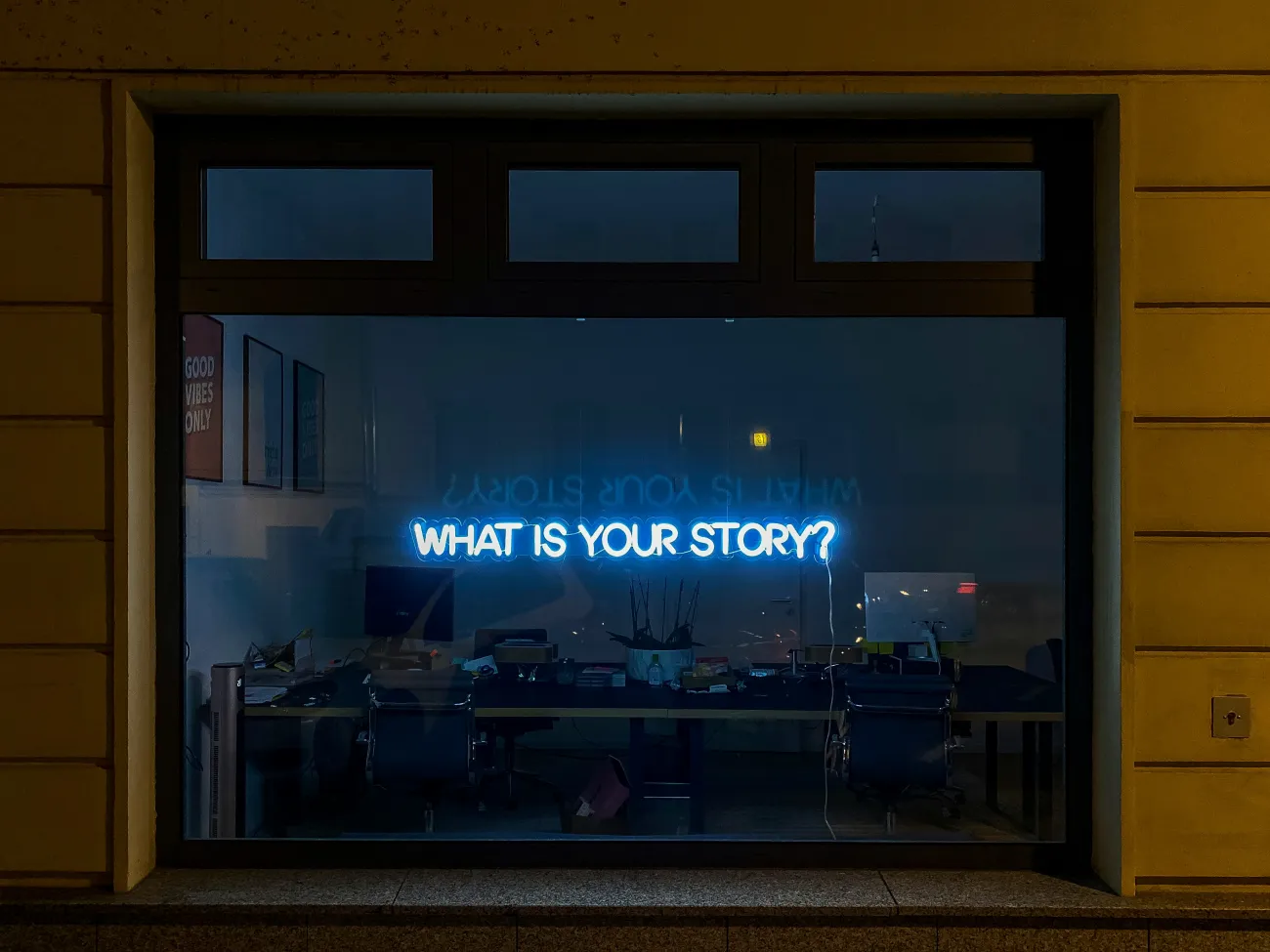 A neon sign in a shop window in Berlin reads "What is your story?" Photo by Etienne Girardet via Unsplash.