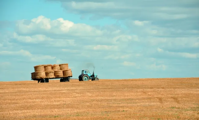 Image of a tractor collecting bales of hay. Photo by Gozha Net via Unsplash.