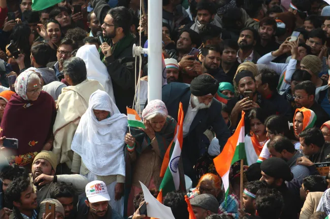 Image: Protester’s surrounding a pole holding Indian flags. Photo by Shakeb Tawheed via Pexels