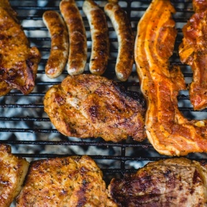 Chicken, bacon, and sausages cooked on a barbeque. Photo by Marcus Spiske via Unsplash.