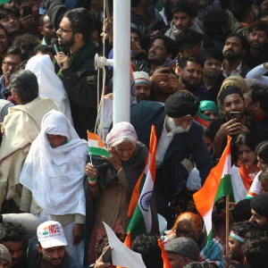 Image: Protester’s surrounding a pole holding Indian flags. Photo by Shakeb Tawheed via Pexels