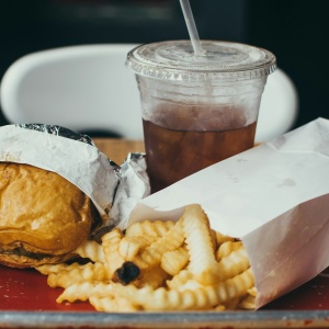 A tray of fast food including a burger, fries, and a drink. Photo by Christopher Williams on Unsplash.